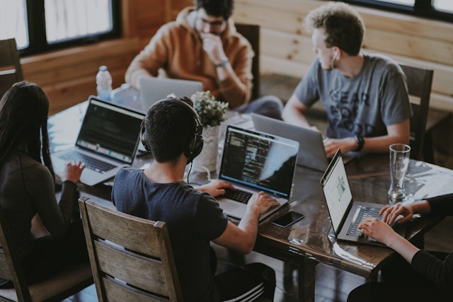 Group of young professionals working together on laptops in a collaborative workspace.